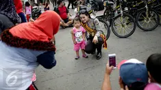 Seorang anak berfoto dengan polisi wanita (Polwan) dari kesatuan Samapta Bhayangkara (Sabhara) Polda Metro Jaya di kawasan Bundaran HI, Jakarta, Minggu (26/3). Polwan bersepeda ini memantau kelancaran car free day. (Liputan6.com/Faizal Fanani)