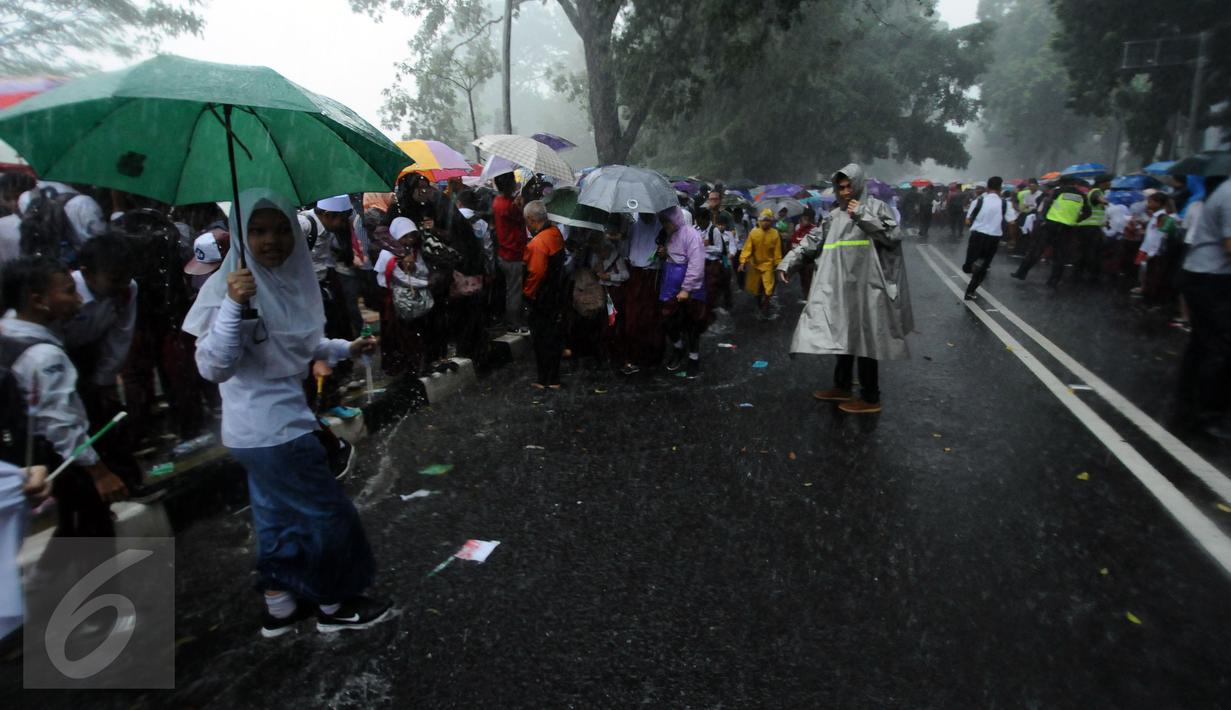 Sejumlah pelajar SD bermain hujan usai menyambut kedatangan Raja Salman di sekitar Istana Bogor, Rabu (1/3). Kedatangan Raja Salman bin Abdulaziz ke Istana Bogor disambut puluhan ribu pelajar dan warga. (Liputan6.com/Helmi Fithriansyah) 