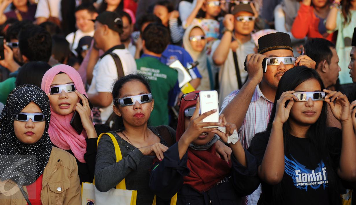 Beberapa warga menggunakan kacamata khusus untuk melihat proses gerhana matahari di sekitar Taman Ismail Marzuki, Jakarta, Rabu (9/3/2016). Di Jakarta, fenomena gerhana matahari 90% bisa diamati selama 2,11 menit. (Liputan6.com/Helmi Fithriansyah)   