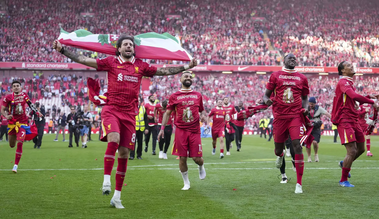Pemain Liverpool, Dominik Szoboszlai melakukan selebrasi dengan membawa bendera Hungaria setelah membawa timnya memastikan gelar juara Liga Inggris 2024/2025 di Anfield, Liverpool, Inggris, Minggu (27/04/2025) waktu setempat. (AP Photo/Jon Super)
