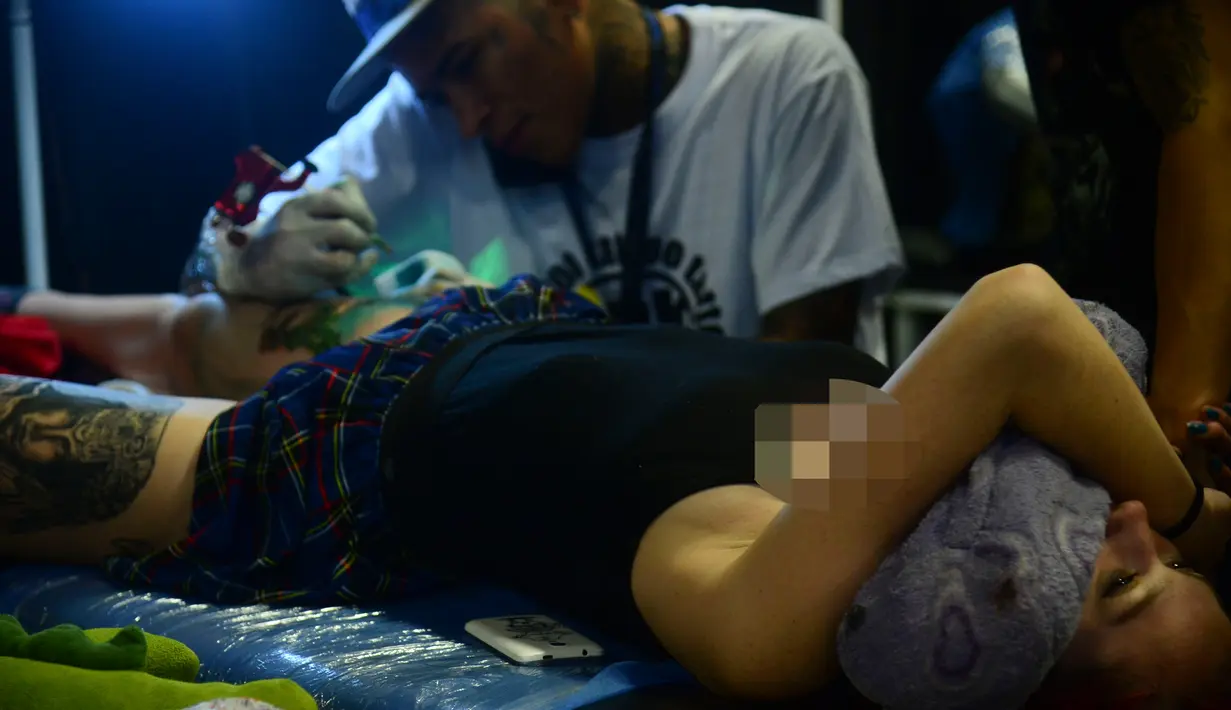 Seorang wanita dibuatkan tato di salah satu stan saat mengunjungi Expotattoo Colombia 2016 di Medellin, Kolombia, (16/7). Sejumlah wanita tampak antusias untuk mentato tubuhnya di festival tato terbesar di negara tersebut. (AFP PHOTO/RAUL Arboleda)