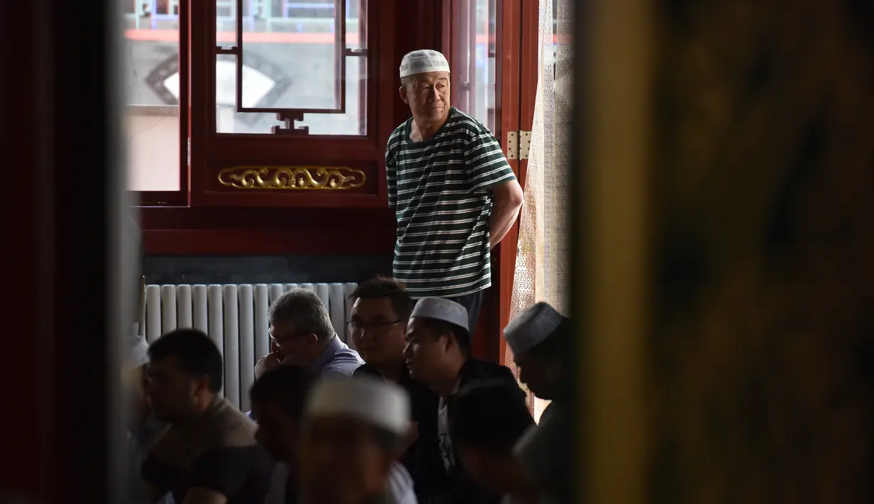 Seorang pria Muslim berdiri sambil mendengarkan ceramah sebelum salat Jumat pertama pada bulan Ramadan 1440 H di sebuah masjid di Beijing (10/5/2019). (AFP Photo/Greg Baker)