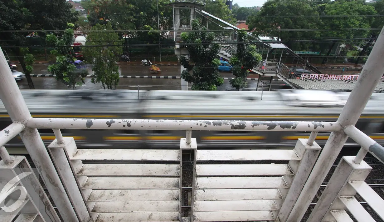 Kereta melintas di dekat JPO di kawasan Tanjung Barat, Jakarta, Jumat (11/11). Buruknya desain menyebabkan JPO tersebut tidak tersambung, sehingga warga harus membeli tiket kereta jika ingin menyeberang. (Liputan6.com/Immanuel Antonius)