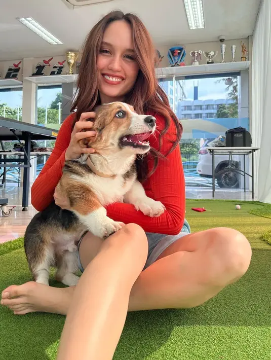 Potret menggemaskan Cinta Laura bermain dengan anjing. Ia mengenakan atasan lengan panjang berwarna merah, dipadunya dengan short denim pants. [Foto: Instagram/claurakiehl]