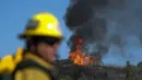 Petugas pemadam kebakaran bekerja pada kebakaran hutan di dekat rumah di Whittier, California, Kamis (10/2/2022). Setidaknya dua rumah hancur dalam kebakaran semak yang menghitamkan sekitar empat hektar di daerah Whittier. (AP Photo/Ringo H.W. Chiu)