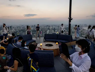 Orang-orang memandangi cakrawala dari dek observasi di gedung pencakar langit King Power Mahanakhon saat matahari terbenam di Bangkok, pada 25 Oktober 2021. Dari ketinggian 314 meter, para pengunjung dapat melihat pemandangan ibu kota Thailand. (Jack TAYLOR / AFP)