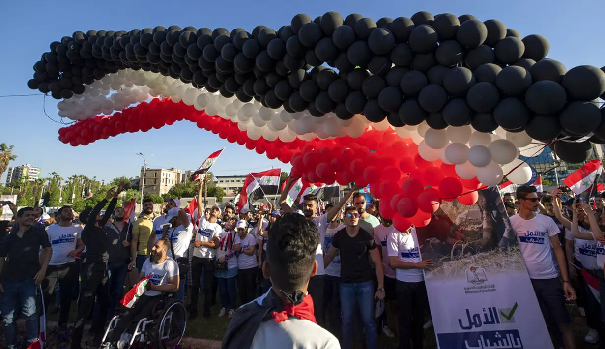 Pendukung Presiden Suriah Bashar Assad melepaskan ratusan balon dengan warna bendera Suriah pada pertemuan di Omayyid Square, Damaskus, Suriah, Minggu (23/5/2021). Pemilihan presiden di negara yang dilanda perang itu akan diadakan pada 26 Mei. (AP Photo/Hassan Ammar)