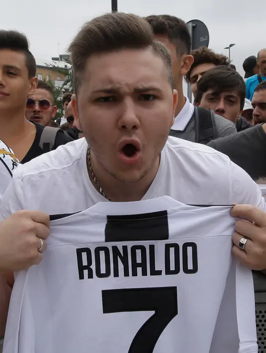Suporter Juventus menunjukkan jersey saat menyambut kedatangan pemain baru Juventus Cristiano Ronaldo untuk menjalani tes medis di pusat layanan kesehatan Juventus (J-Medical) di Turin, Italia, (16/7). (AP Photo/Luca Bruno)
