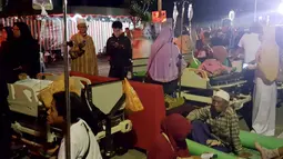 Pasien berada diluar rumah sakit saat gempa mengguncang Lombok Utara, NTB Minggu malam (5/8). BMKG menyatakan, potensi tsunami akibat gempa 7 SR, telah terdeteksi di Carik pada pukul 18.48 WIB. (AFP Photo/Rita Siswati)