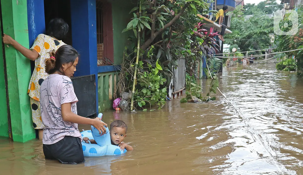 Warga beraktivitas di tengah banjir yang melanda kawasan Cipinang Melayu, Jakarta Timur, Jumat (19/2/2021). Banjir di kawasan tersebut akibat curah hujan yang tinggi dan meluapnya air dari Kali Sunter. (Liputan6.com/Herman Zakharia)