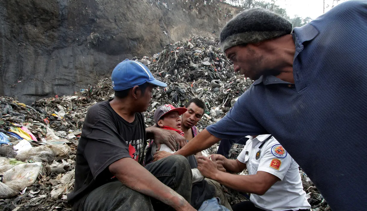 Seorang pemulung dihibur rekan-rekannya dan petugas pemadam kebakaran setelah sepupunya meninggal tertimpa longsoran ribuan kubik sampah di Tempat Pembuangan Akhir (TPA)  di Guatemala City, Guatemala, Rabu (27/4). (REUTERS/Josue Decavele)