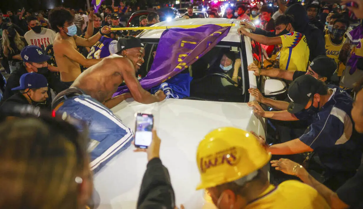 Fans LA Lakers melakukan selebrasi turun ke jalan usai menjuarai NBA 2020 di Los Angeles, Senin (12/10/2020).
LA Lakers menjadi juara NBA 2020 setelah mengalahkan Miami Heat dengan skor 106-93 dalam final gim ke enam. (AP Photo/Jintak Han)