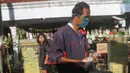 Seorang pria membawa sekantong sayuran yang digantung pada pagar rumah di Gang Palautan, Cilodong, Depok, Jumat (21/1/2022). Warga Rt 04 Rw 01 di kawasan tersebut secara swadaya berbagi sayuran, beras, dan bumbu masak secara gratis setiap hari Jumat.  (Liputan6.com/Herman Zakharia)