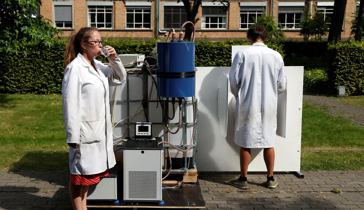 Ilmuwan Belgia, Marjolein Vanoppen dan Sebastiaan Derese menjajal mesin yang bisa mengubah air seni menjadi air yang layak diminum dan menjadi pupuk dengan bantuan energi matahari di University of Ghent, Belgia, Selasa (26/7). (REUTERS/Francois Lenoir)