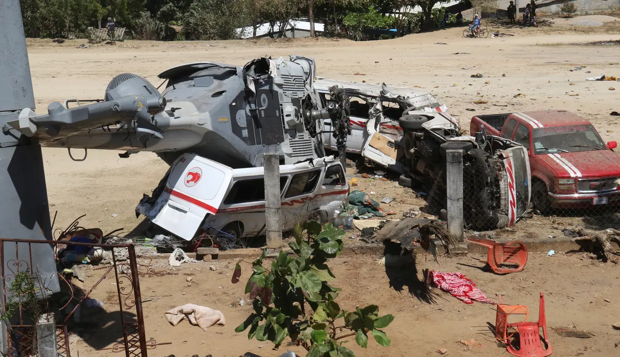 Sebuah helikopter milter Meksiko jatuh menimpa mobil van di Santiago Jamiltepec, negara bagian Oaxaca, Sabtu (17/2). Helikopter nahas itu jatuh di atas dua mobil van di sebuah lapangan terbuka ketika berupaya mendarat. (AP/Luis Alberto Cruz Hernandez)