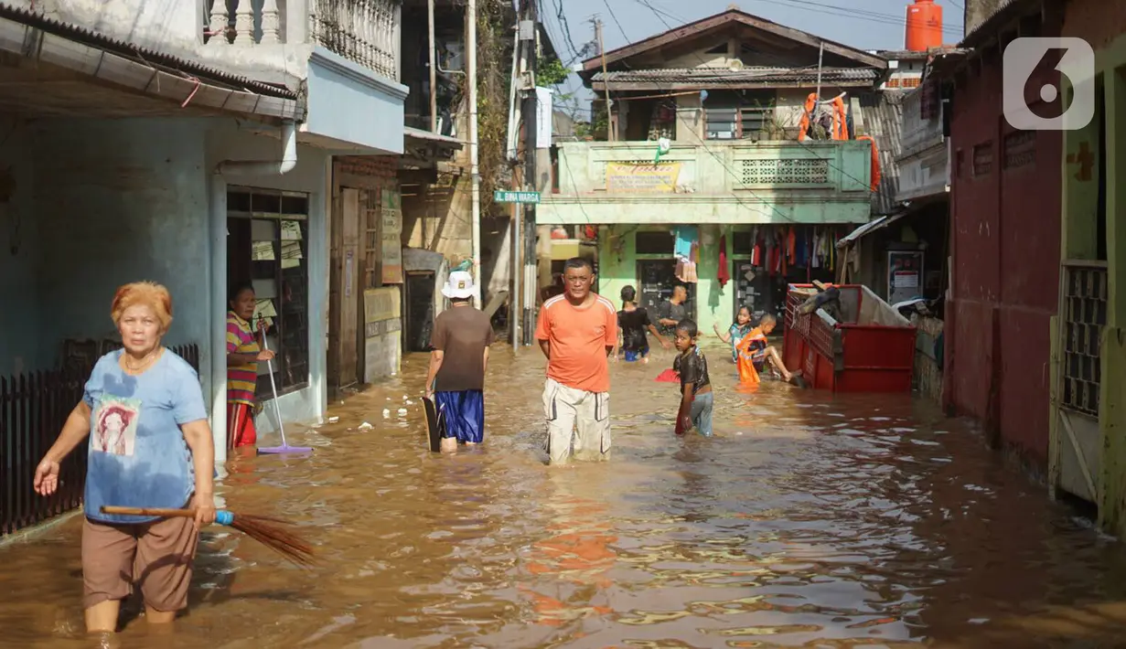 Warga beraktivitas di tengah banjir yang merendam kawasan Rawajati, Jakarta Selatan, Sabtu (8/2/2020). Hujan yang terjadi semalaman menyebabkan Sungai Ciliwung kembali meluap hingga membuat rumah warga di kawasan tersebut terendam air setinggi 50 cm hingga 1 m. (Liputan6.com/Immanuel Antonius)
