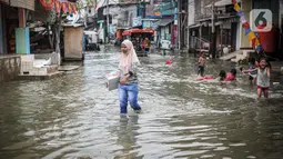 Warga beraktivitas saat banjir rob di Muara Angke, Jakarta, Jumat (25/11/2022). Badan Penanggulangan Bencana Daerah (BPBD) DKI Jakarta mengimbau agar warga di pesisir Jakarta mengantisipasi banjir pesisir atau rob selama 22-28 November 2022. (Liputan6.com/Faizal Fanani)