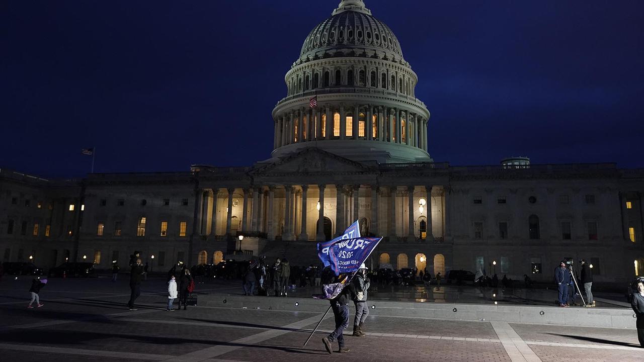 Seorang pendukung Presiden Donald Trump memegang bendera Trump di luar Gedung Capitol AS pada Rabu, 6 Januari, di Washington. (Jacquelyn Martin / AP)
