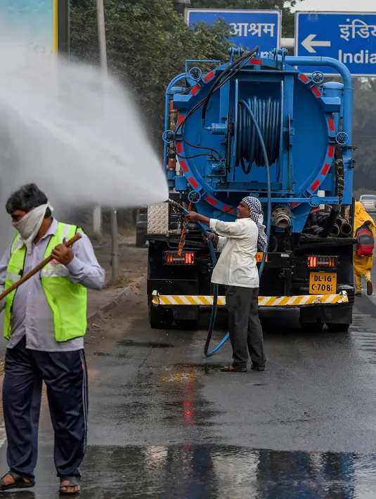 Petugas menyemprotkan air ke pohon-pohon di pinggir jalan New Delhi, India, Rabu (6/11/2019). Hal tersebut dilakukan dalam upaya untuk mengurangi polusi udara dengan memerangi akumulasi debu. (Photo by Prakash SINGH / AFP)