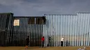 Sejumlah orang mengecat pagar perbatasan antara Meksiko dan Amerika Serikat di Playas Tijuana, Meksiko (10/12). (Reuters/Jorge Duenes)