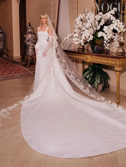Tampilan Nicola dilengkapi dengan sarung tangan yang diberi sematan detail renda Prancis yang mewah. Dilengkapi pula dengan veil dan train panjang yang menjuntai sampai ke lantai, sesuai dengan gaun impian Nicola. (Instagram/britishvogue).
