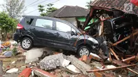Dua unit mobil tertimbun reruntuhan rumah yang rusak setelah tsunami menerjang kawasan Anyer, Banten, Minggu (23/12). Tsunami menerjang pantai di Selat Sunda, khususnya di daerah Pandenglang, Lampung Selatan, dan Serang. (Liputan6.com/Angga Yuniar)