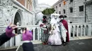 Wisatawan mengambil gambar sejumlah peserta yang menggunakan kostum dan topeng di depan Ponte dei Sospiri (Bridge of Sighs) saat mengikuti Karnaval Venesia, Italia, Sabtu (30/1). (REUTERS/Alessandro Bianchi)