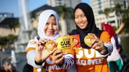 Dua anak muda dari Jaklovers menunjukkan pin saat aksi simpatik mendukung Wali Kota Surabaya Tri Rismaharini maju sebagai calon gubernur (cagub) pada Pilkada DKI 2017, di Bundaran Patung Kuda, Jakarta , Minggu (31/7). (Liputan6.com/Faizal Fanani)