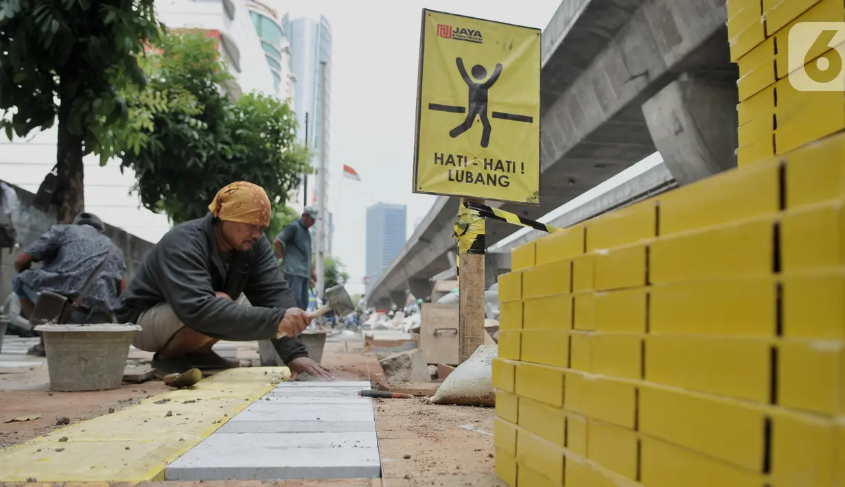 Pekerja menyelesaikan proyek revitalisasi trotoar di kawasan Kuningan, Jakarta, Senin (4/11/2019). Dinas Bina Marga DKI Jakarta menganggarkan biaya proyek revitalisasi trotoar sebesar Rp 1,1 triliun. (merdeka.com/Iqbal Nugroho)
