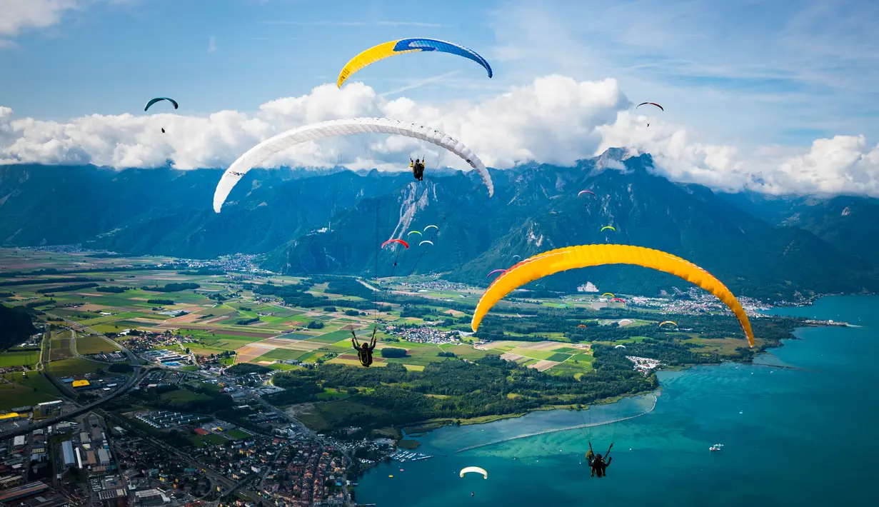 Puluhan paraglider melakukan penerbangan menuju pendaratan "Acro Show" di atas Danau Jenewa di Villeneuve, Swiss (20/8). Olahraga paragliding ini untuk tujuan rekreasi atau kompetisi. (Valentin Flauraud / Keystone via AP)