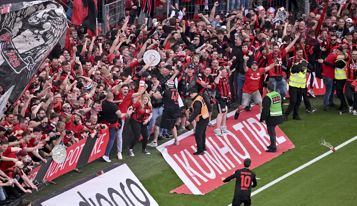 Suporter Bayer Leverkusen merayakan gol yang dicetak oleh Florian Wirtz (10) pada laga lanjutan Liga Jerman 2023/2024 melawan Weder Bremen di BayArena, Leverkusen, Jerman, Senin (15/04/2024) WIB. (AP Photo/DPA/David Inderlied)