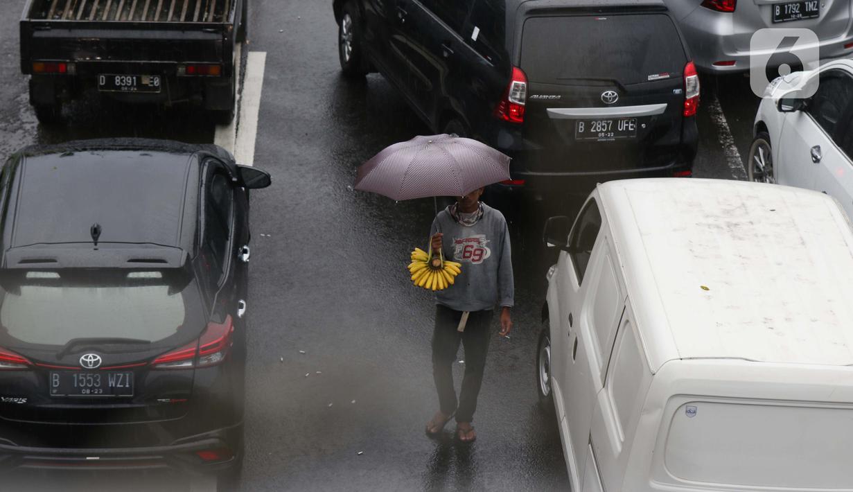 Seorang pedagang asongan menawarkan dagangan kepada pengendara di jalan tol Jagorawi yang sedang menanti waktu buka tutup jalur menuju kawasan wisata puncak, Bogor, Jawa Barat, Sabtu (31/10/2020). (Liputan6.com/Helmi Fithriansyah)