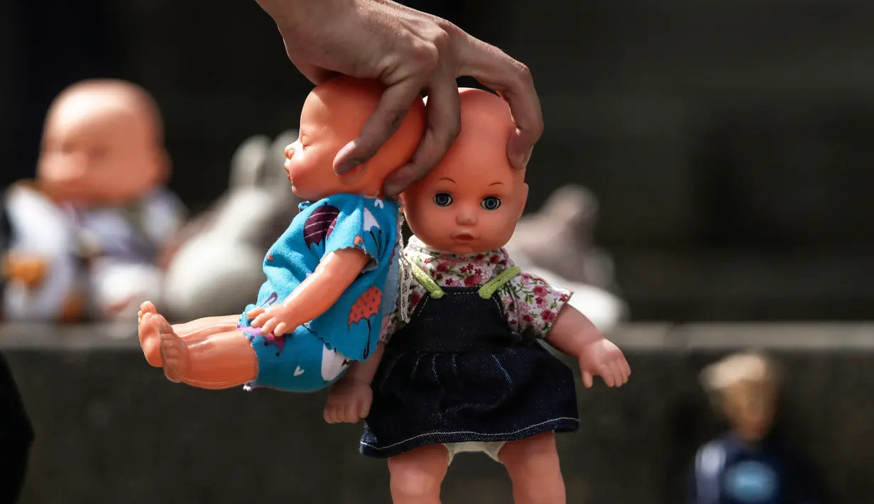 Seseorang meletakkan boneka mainan di halaman gedung Kongres Kolombia untuk memprotes kekerasan seksual terhadap anak di Bogota, Selasa (20/11). Protes ini untuk meningkatkan kesadaran tentang tanggung jawab perlindungan anak-anak. (DANIEL MUNOZ/AFP)