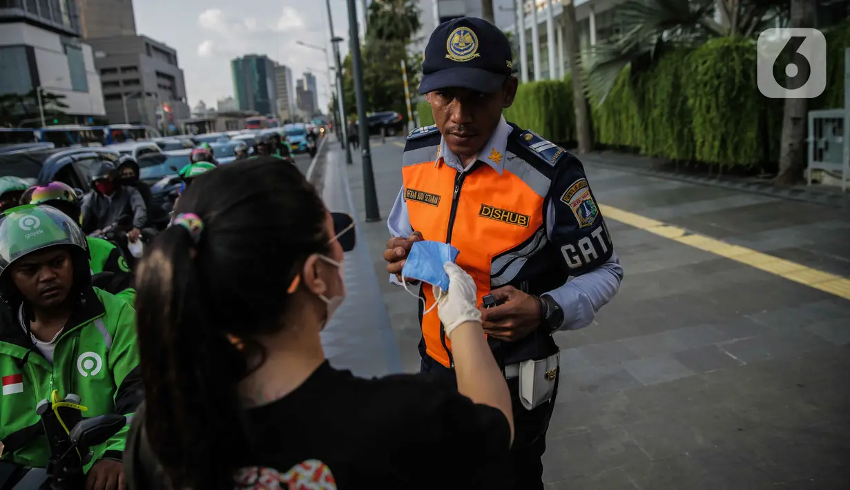 Relawan membagikan masker kepada petugas Dishub di Bundaran HI, Jakarta, Selasa (17/3/2020). Sebanyak 3.000 masker dibagikan gratis kepada pengguna jalan sebagai salah satu bentuk keprihatinan sekaligus berpartisipasi dalam upaya mencegah penyebaran virus corona COVID-19 (Liputan6.com/Faizal Fanani)