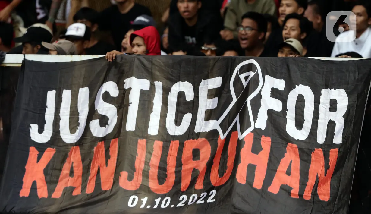 Pendukung timnas Indonesia membentang spanduk bertuliskan “Justice for Kanjuruhan” saat menyaksikan laga kualifikasi Grup A Piala AFF 2022 antara Indonesia melawan Kamboja di di Stadion Utama Gelora Bung Karno, Jakarta, Jumat (23/12/2022). Mereka menyuarakan pengusutan tuntas kasus atas Tragedi Kanjuruhan yang terjadi pada awal Oktober 2022 lalu. (Liputan6.com/Helmi Fithriansyah)