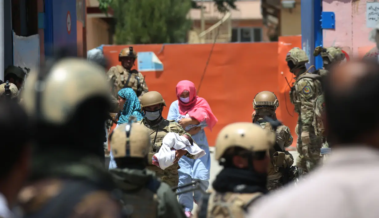 Seorang anggota keamanan dan seorang pekerja kesehatan menggendong bayi dari lokasi serangan di sebuah rumah sakit di Kabul, ibu kota Afghanistan (12/5/2020).  (Xinhua/Rahmatullah Alizadah)