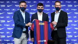 Penyerang baru Barcelona Pedri (tengah) berpose dengan jersey barunya di samping presiden klub Josep Maria Bartomeu (kiri) dan direktur olahraga Ramon Planes selama presentasi resminya di stadion Camp Nou di Barcelona (20/8/2020). Pemain 17 tahun itu diikat selama dua tahun. (AFP/Josep Lago)