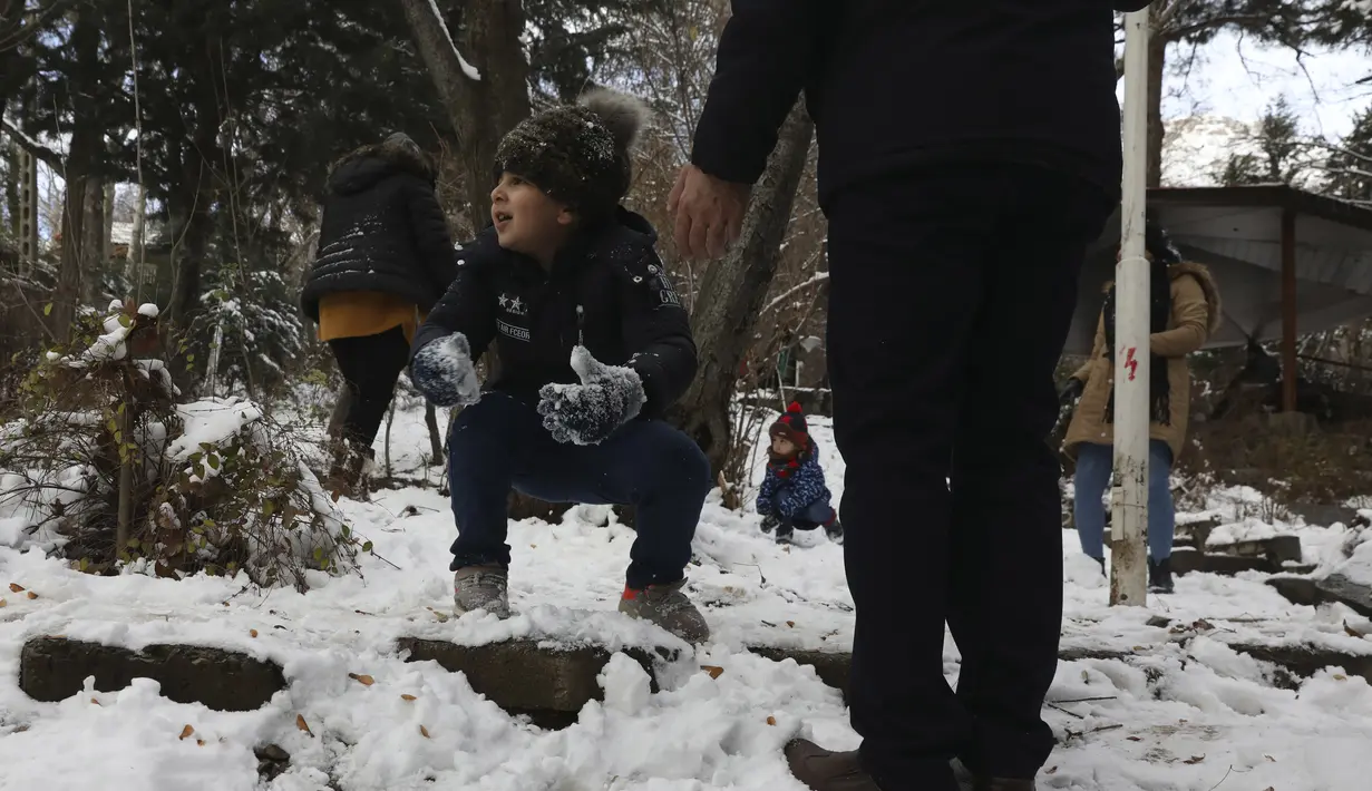 Seorang bocah lelaki bermain salju bersama keluarganya saat menghabiskan akhir pekan mereka di sebuah taman di Teheran utara, Iran, Jumat (25/12/2020). Musim dingin di Iran biasanya dimulai dari bulan Desember hingga Februari.  (AP Photo/Vahid Salemi)