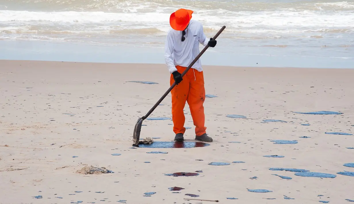 Gambar yang dirilis 4 Oktober 2019 menunjukkan pekerja membersihkan minyak di pantai Pontal de Coruripe di Coruripe, negara bagian Alagoas, Brasil. Tumpahan minyak yang telah mengering sejak beberapa pekan terakhir telah mencemari 132 pantai di kawasan timur laut Brasil. (HO/ADEMAS /AFP)