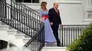 Presiden AS Donald Trump menggandeng tangan Melania Trump sambil menuruni tangga untuk menyambut keluarga militer pada acara piknik di Gedung Putih, Rabu (4/7). Pasangan yang jarang bergandengan tangan di depan umum itu tampak serasi. (AP/Alex Brandon)