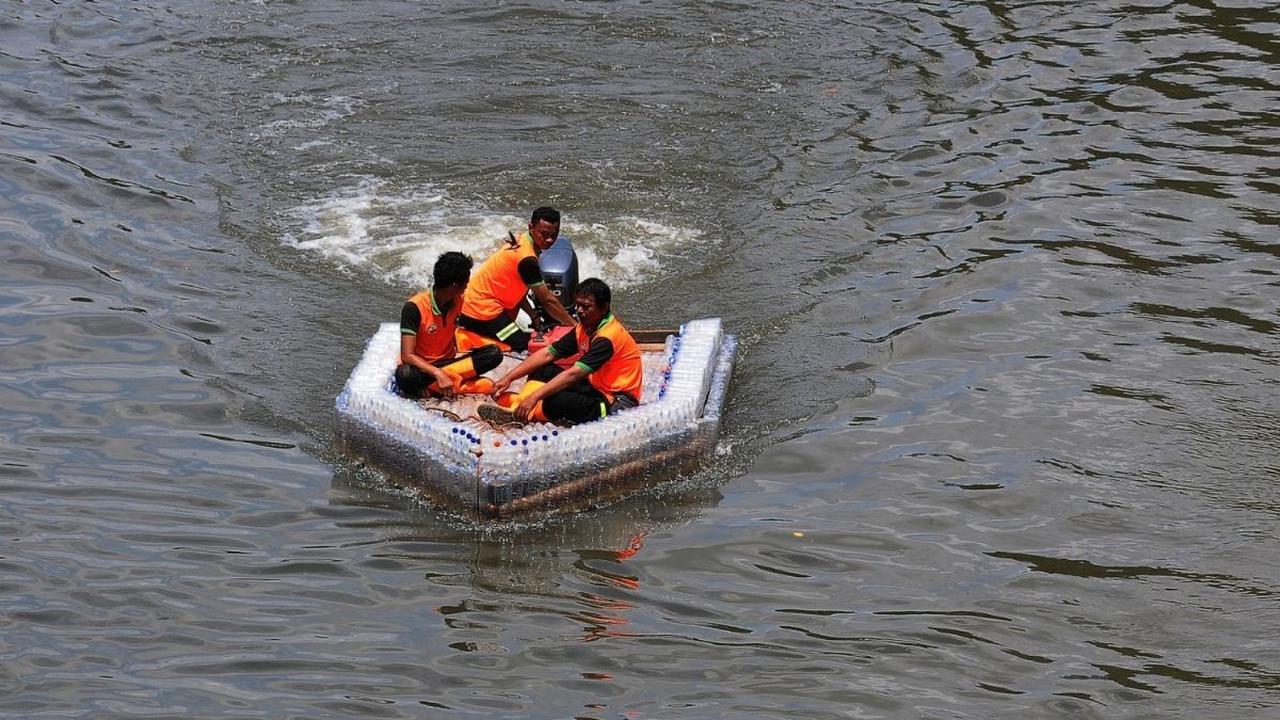 Petugas UPS Badan Air melakukan uji coba terhadap ketahanan dan keseimbangan perahu yang terbuat dari botol plastik bekas di aliran Kanal Banjir Timur (KBT), Jakarta, Selasa (5/3/2024). Foto: merdeka.com / Imam Buhori