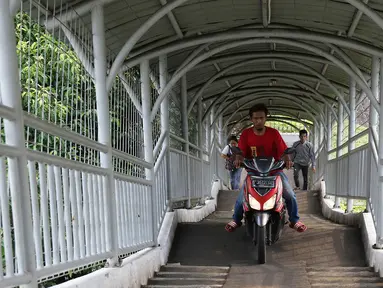 Pengendara sepeda motor melewati Jembatan Penyeberangan Orang (JPO) di kawasan Pasar Minggu, Jakarta, Selasa (17/10). JPO yang diperuntukkan bagi pejalan kaki itu sering dimanfaatkan pengendara motor sebagai jalan pintas. (Liputan6.com/Immanuel Antonius)