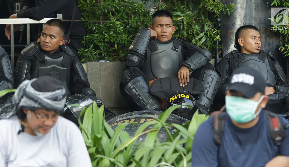 Personil kepolisian dari satuan Brimob beristirahat saat menjaga aksi unjuk rasa yang dilakukan Gerakan Nasional Kedaulatan Rakyat di depan Gedung Bawaslu, Jakarta, Selasa (21/5/2019). Ribuan aparat keamanan gabungan diterjunkan untuk mengamankan jalannya aksi. (Liputan6.com/Helmi Fithriansyah)