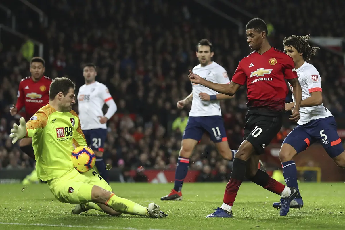 Kiper Bournemouth, Asmir Begovic, menghalau tendangan striker Manchester United, Marcus Rashford, pada laga Premier League di Stadion Old Trafford, Manchester, Minggu (30/12). MU menang 4-1 atas Bournemouth. (AP/Martin Rickett)