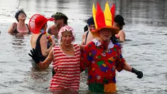 Anggota klub renang es "Berliner Seehunde" merayakan tahun baru dengan berenang di danau Orankesee, Berlin, Jerman (1/1). Diantara mereka ada anggota yang mengenakan pakaian bertema badut. (REUTERS/Fabrizio Bensch)