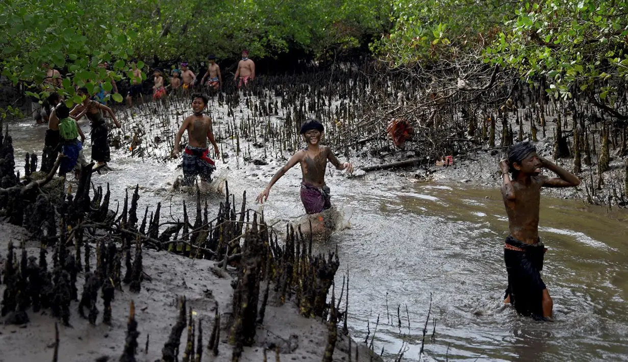 Orang-orang mengambil bagian dalam tradisi mandi lumpur yang dikenal sebagai Mebuug-buugan di Desa Kedonganan, Bali, 4 Maret 2022. Mebuug-buugan diadakan sehari setelah Nyepi yang bertujuan untuk menetralkan sifat buruk. (SONY TUMBELAKA/AFP)