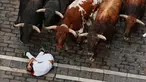 Seorang pengunjung festival terjatuh di depan banteng-banteng aduan Victoriano del Río saat acara lari banteng ketiga di festival San Fermín di Pamplona, Spanyol, Kamis, 9 Juli 2026. (AP Photo/Miguel Oses)