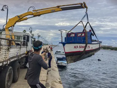 Pekerja memindahkan perahu dari air di teluk Havana, Kuba, Senin, 26 September 2022. Badai Ian semakin kuat saat mendekati ujung barat Kuba di jalur untuk menghantam pantai barat Florida sebagai badai besar paling cepat pada hari Rabu. (Foto AP/Milexsy Duran)