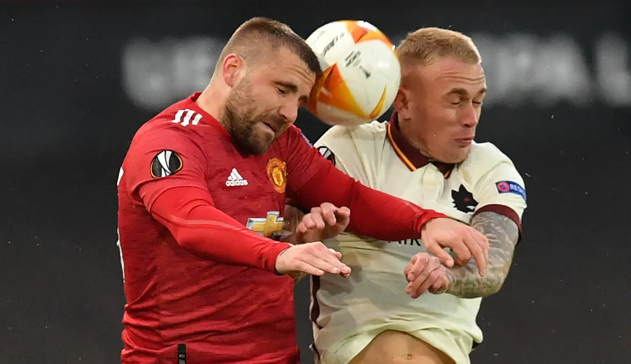 Bek Manchester United, Luke Shaw (kiri) berduel udara dengan bek AS Roma, Rick Karsdorp dalam laga leg pertama semifinal Liga Europa 2020/2021 di Old Trafford Stadium, Manchester, Kamis (29/4/2021). Manchester United menang 6-2 atas AS Roma. (AFP/Paul Ellis)