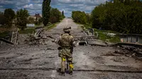 Seorang tentara dari unit pasukan khusus Ukraina Kraken mengamati daerah di jembatan yang hancur di jalan dekat desa Rus'ka Lozova, utara Kharkiv, pada 16 Mei 2022. Ukraina mengatakan pasukannya telah menguasai kembali wilayah di Perbatasan Rusia dekat kota terbesar kedua di negara itu Kharkiv, yang terus-menerus diserang sejak invasi Moskow dimulai. (Dimitar DILKOFF / AFP)